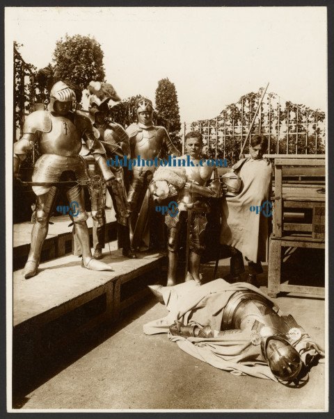 Six Male Models as Ancient Warriors Dressed in Armor, One Playing Dead 1900